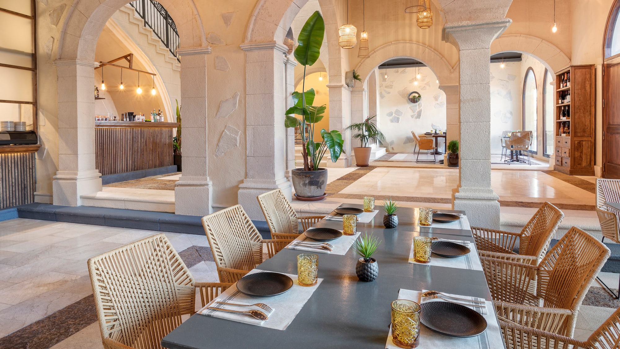 a table with plates and plates on it in a room with stone pillars
