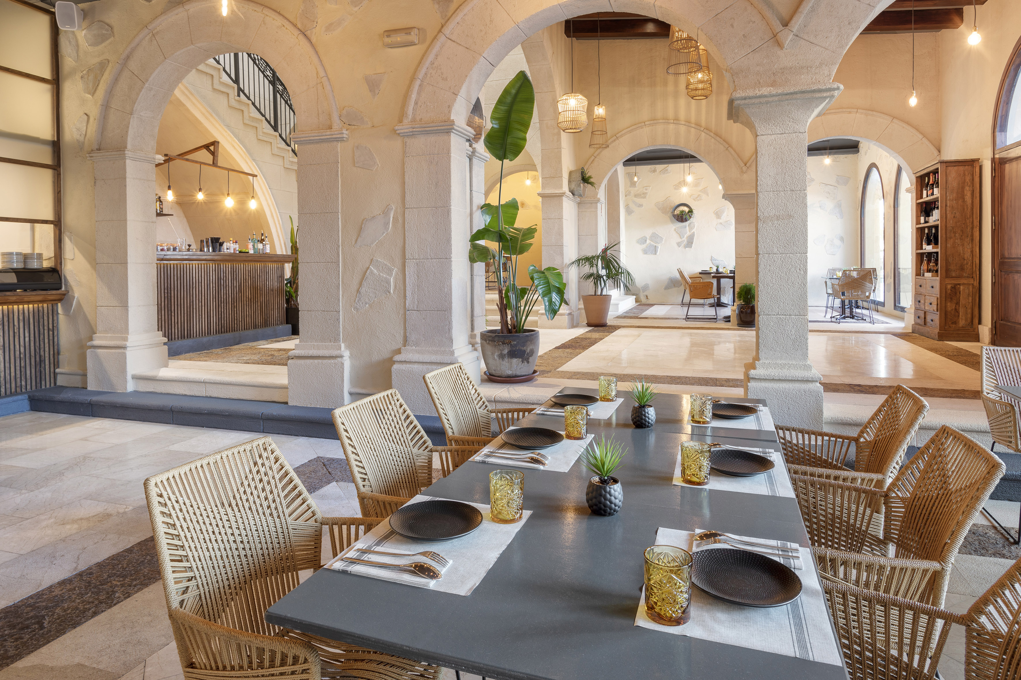 Restaurant dining room with stone arches, set table, and bar.