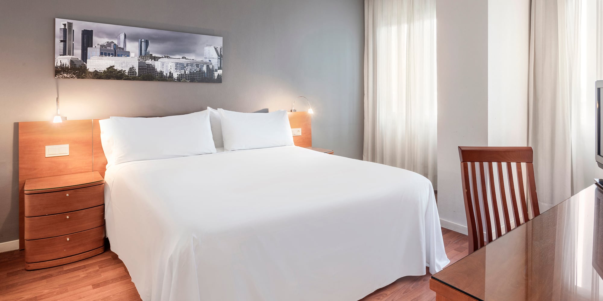 a bed with white sheets and a wood table