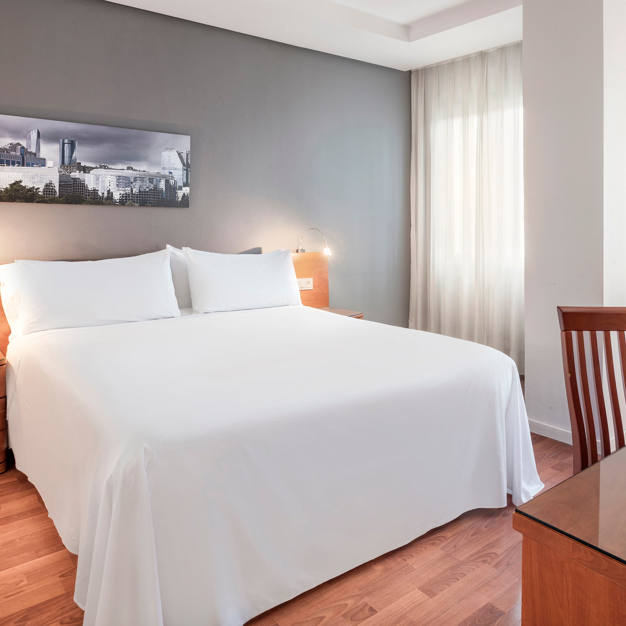 a bed with white sheets and a wood table