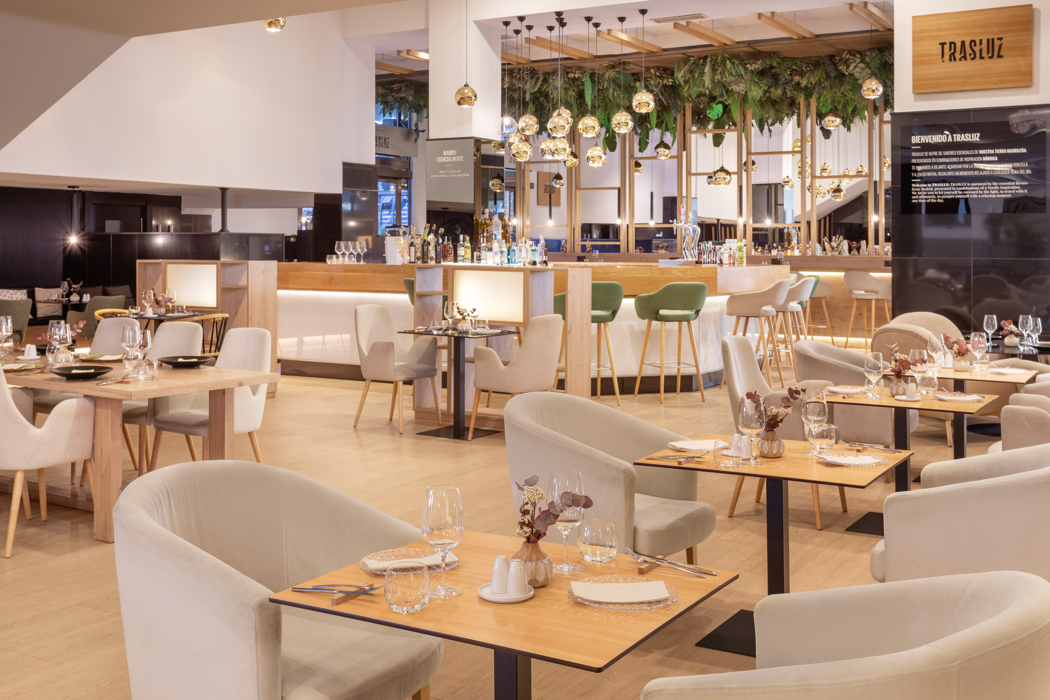 Trasluz restaurant: modern dining area, elegant bar, plush seating, green plants.