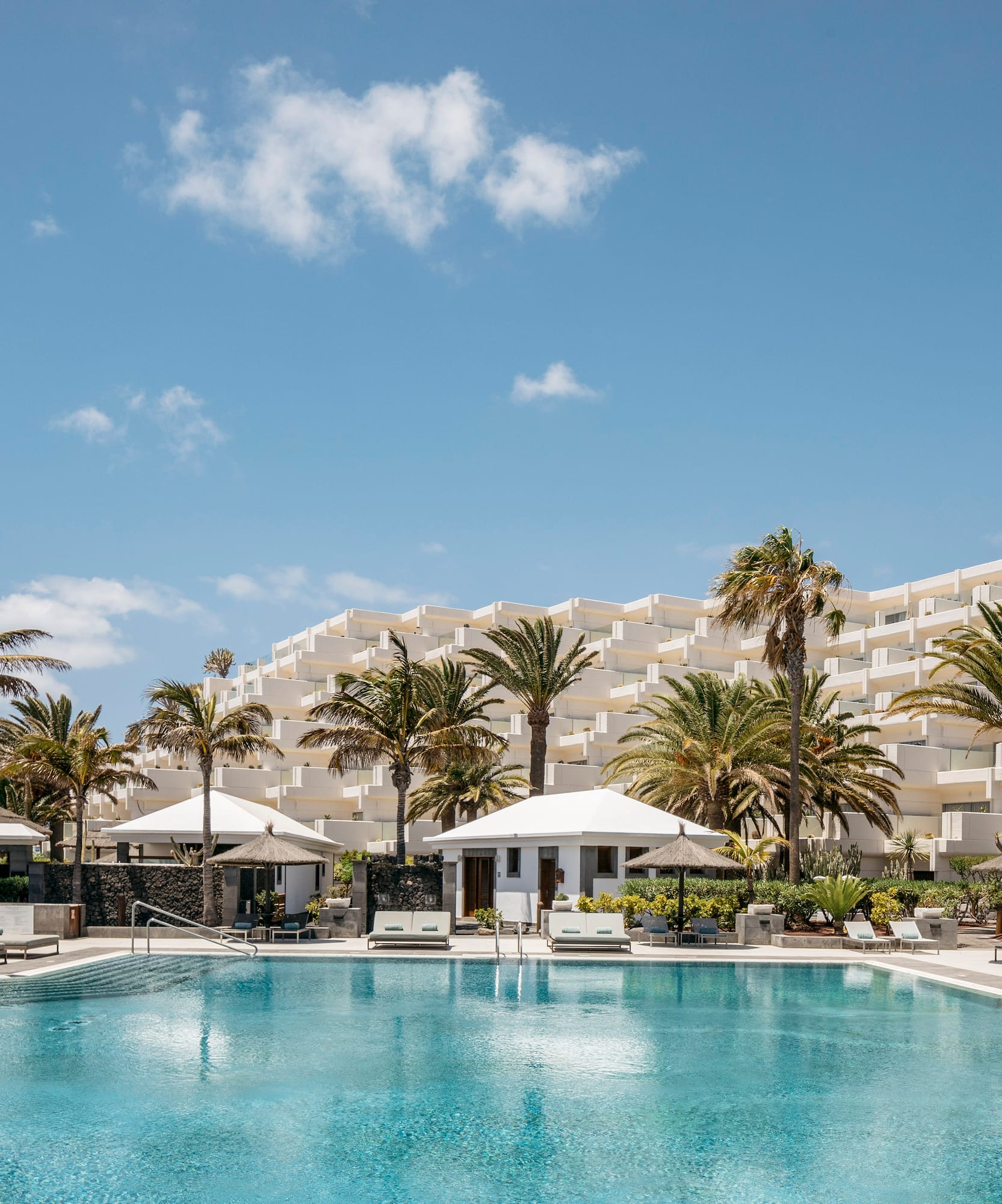 a pool with palm trees and a building in the background