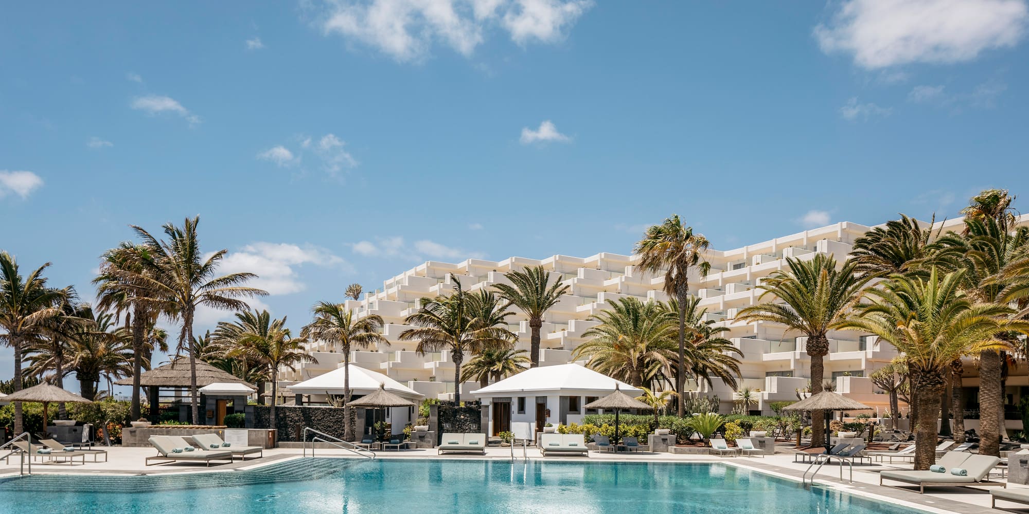 a pool with palm trees and a building in the background