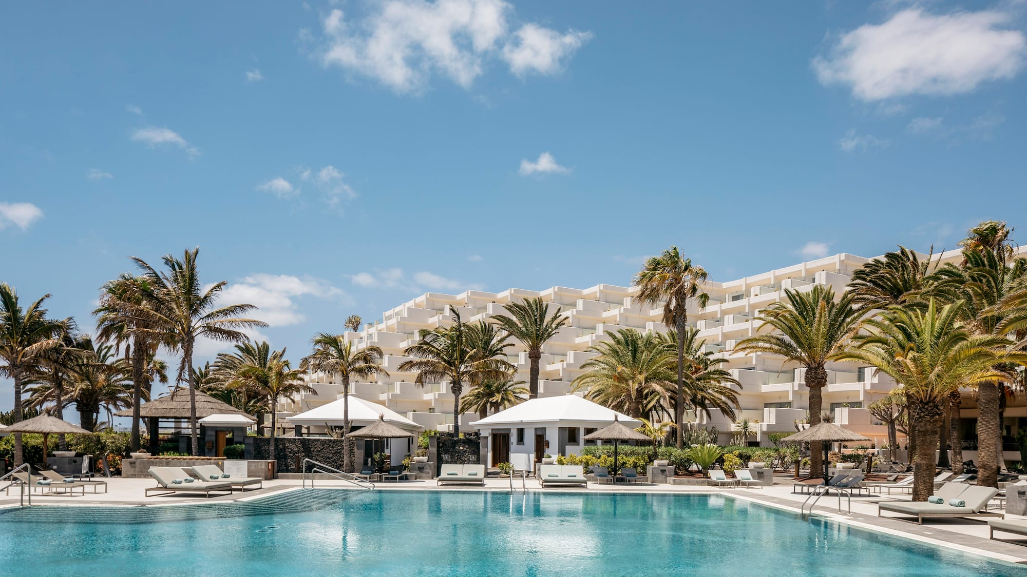 a pool with palm trees and a building in the background