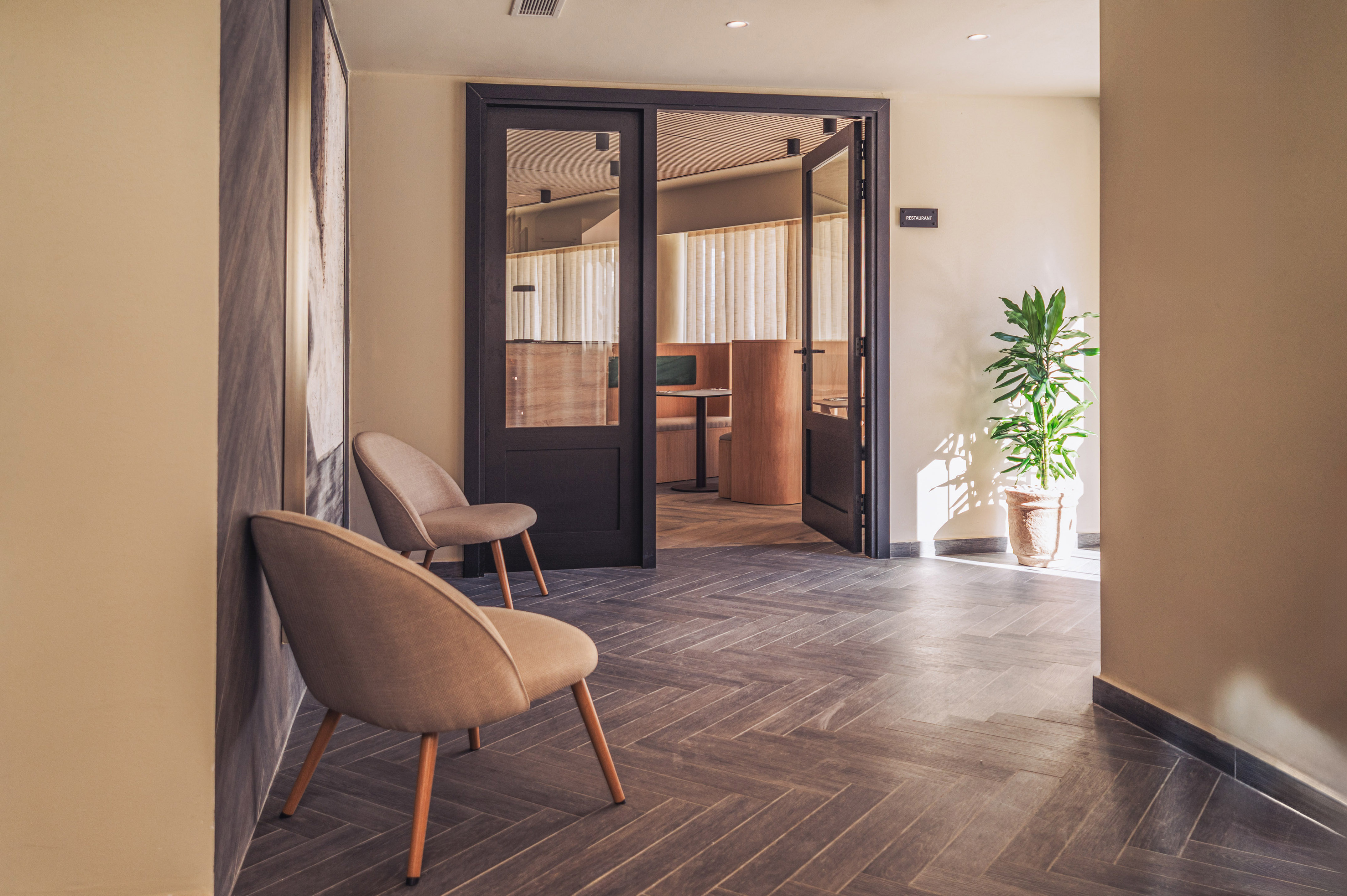 Stylish restaurant entrance with modern chairs and herringbone floor.