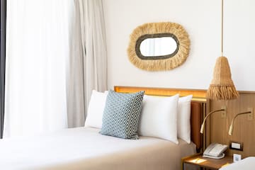 a bed with pillows and a mirror on the wall