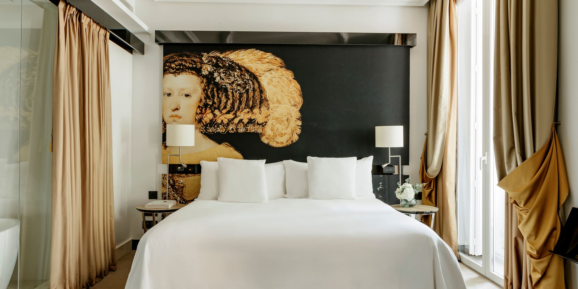 a bed with white sheets and pillows in a room with a large painting on the wall