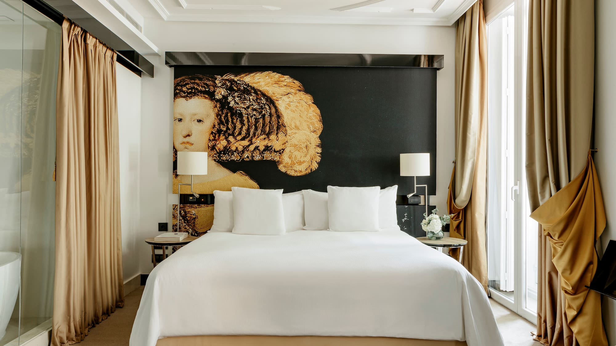 a bed with white sheets and pillows in a room with a large painting on the wall