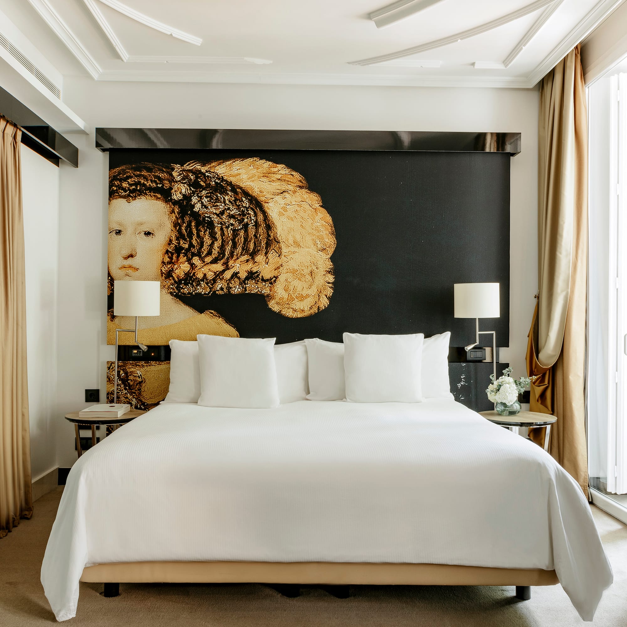 a bed with white sheets and pillows in a room with a large painting on the wall