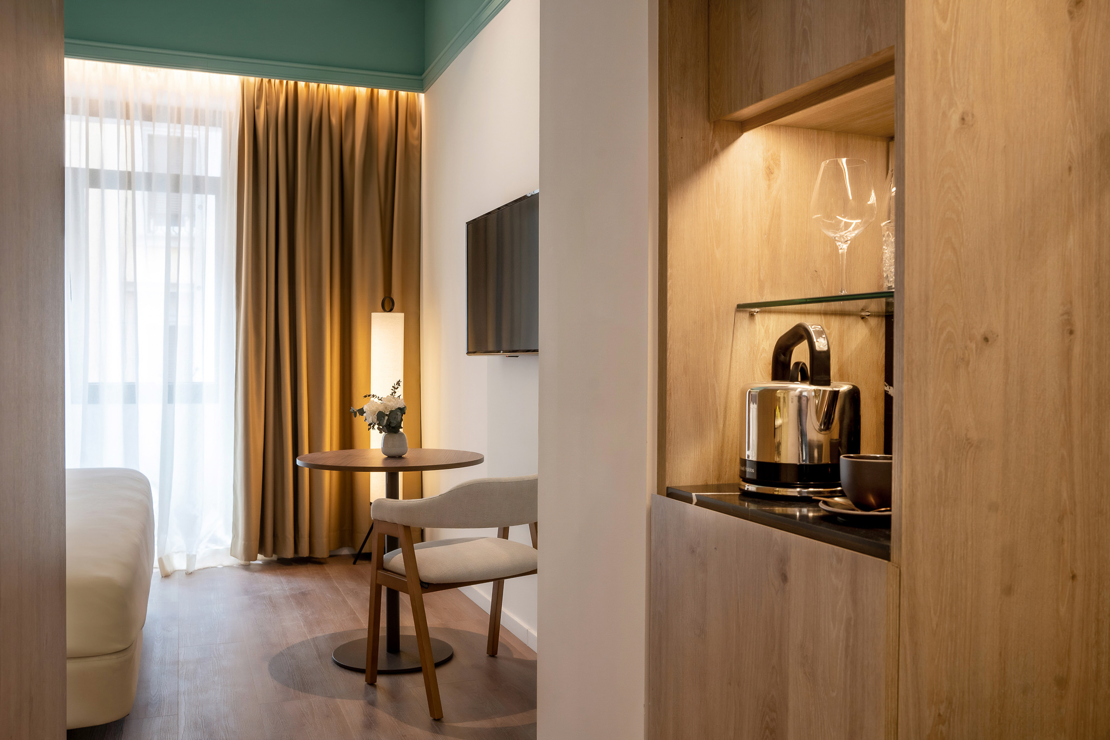 Modern hotel room with coffee station, cozy seating, and large window.