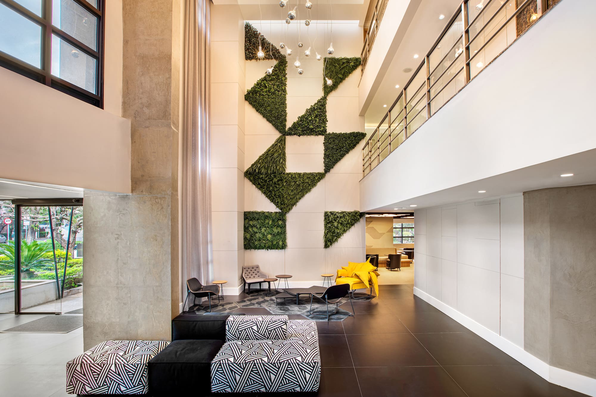 Modern lobby with geometric living wall, diverse seating, and multi-story design.