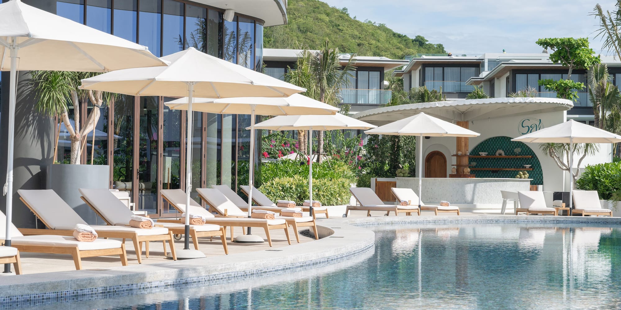 a pool with chairs and umbrellas by a building