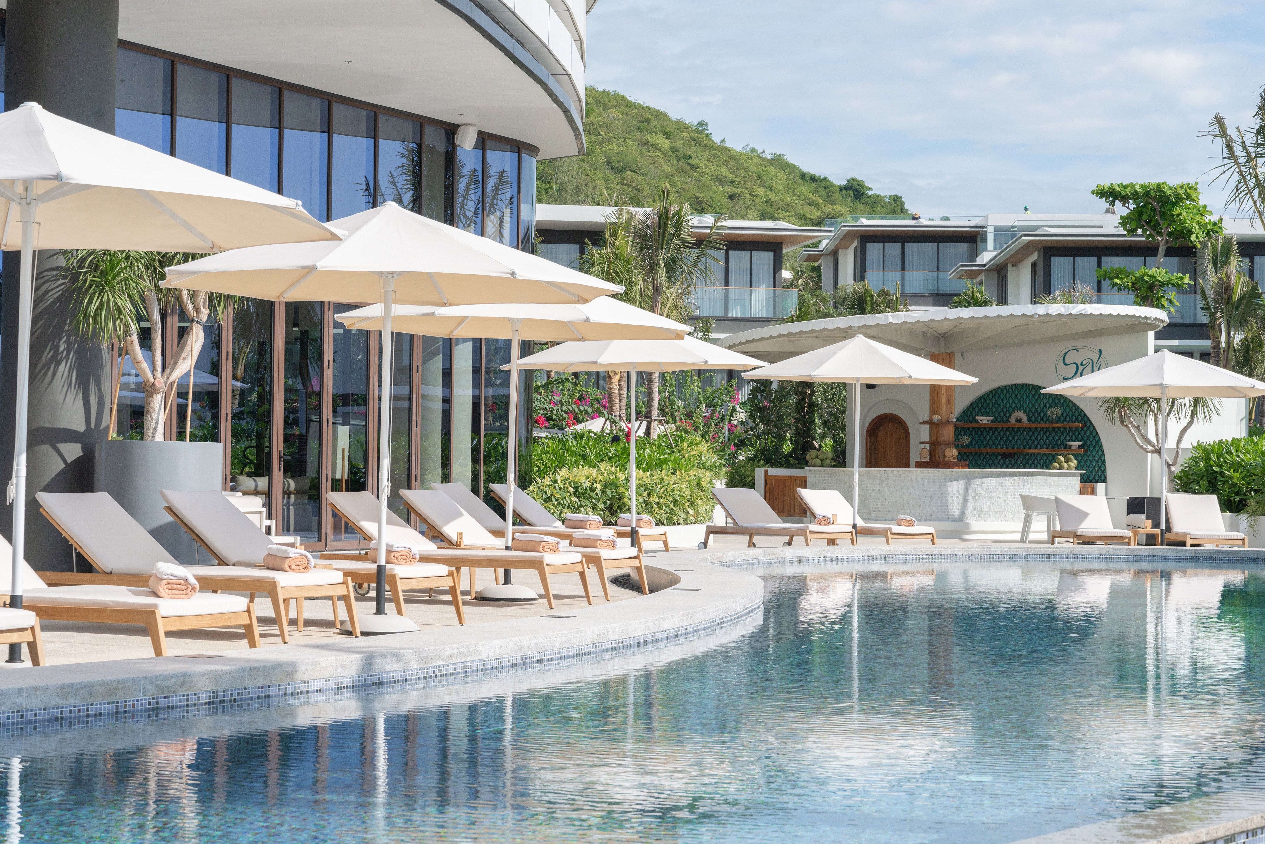 a pool with chairs and umbrellas by a building