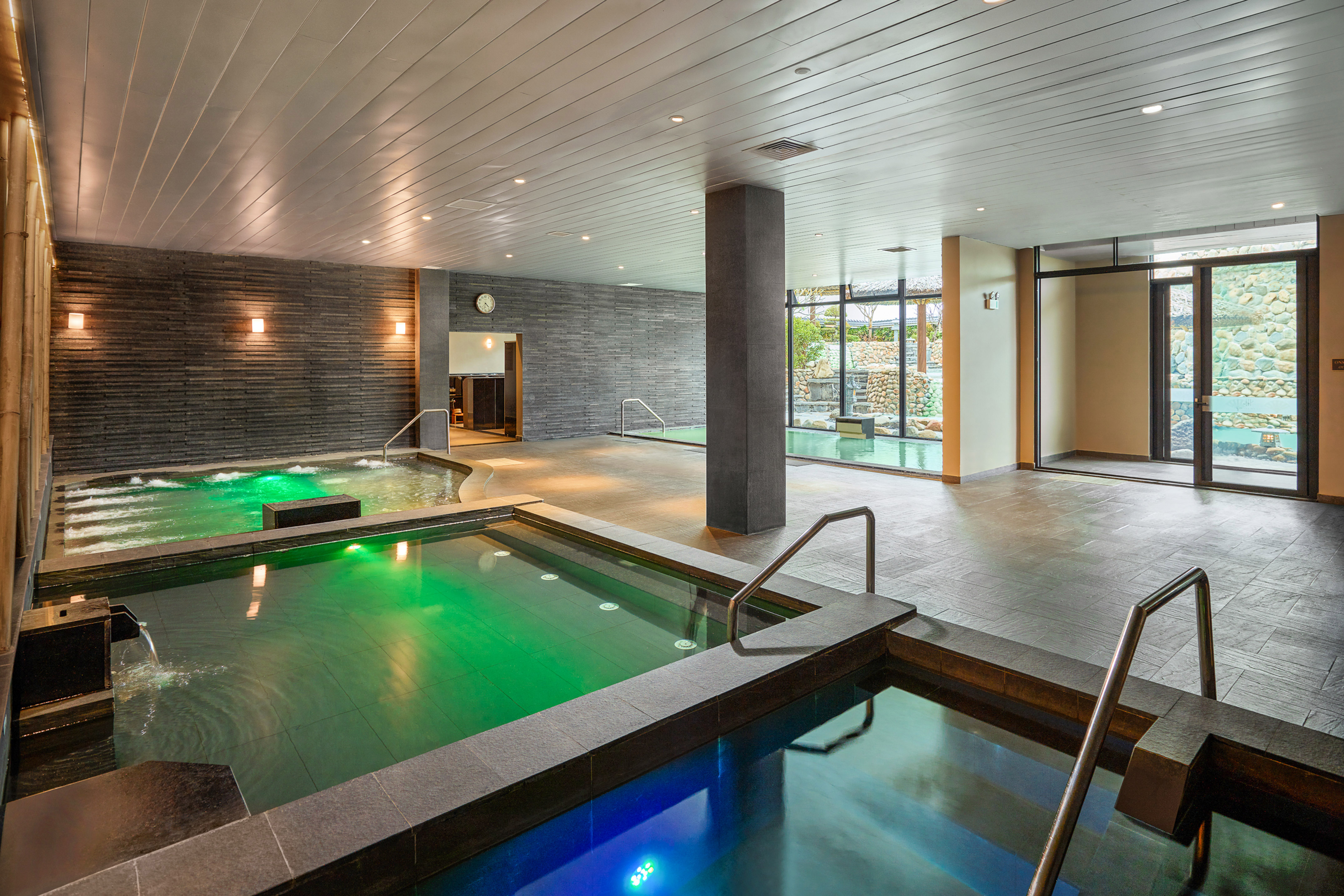 Indoor onsen spa with multiple pools, stone walls, and scenic views.