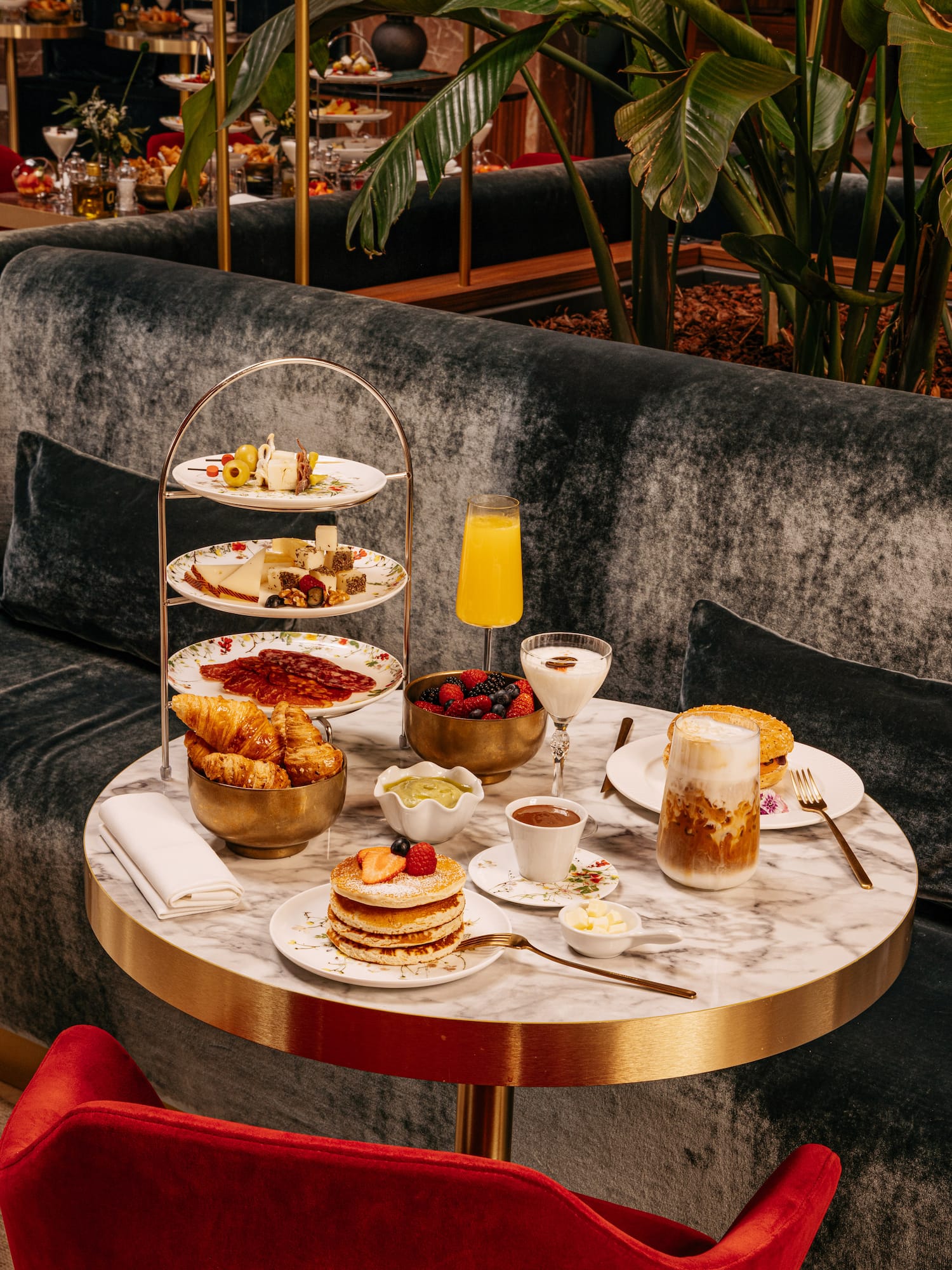 Luxury hotel brunch: pancakes, cheese, pastries, coffee on marble table.
