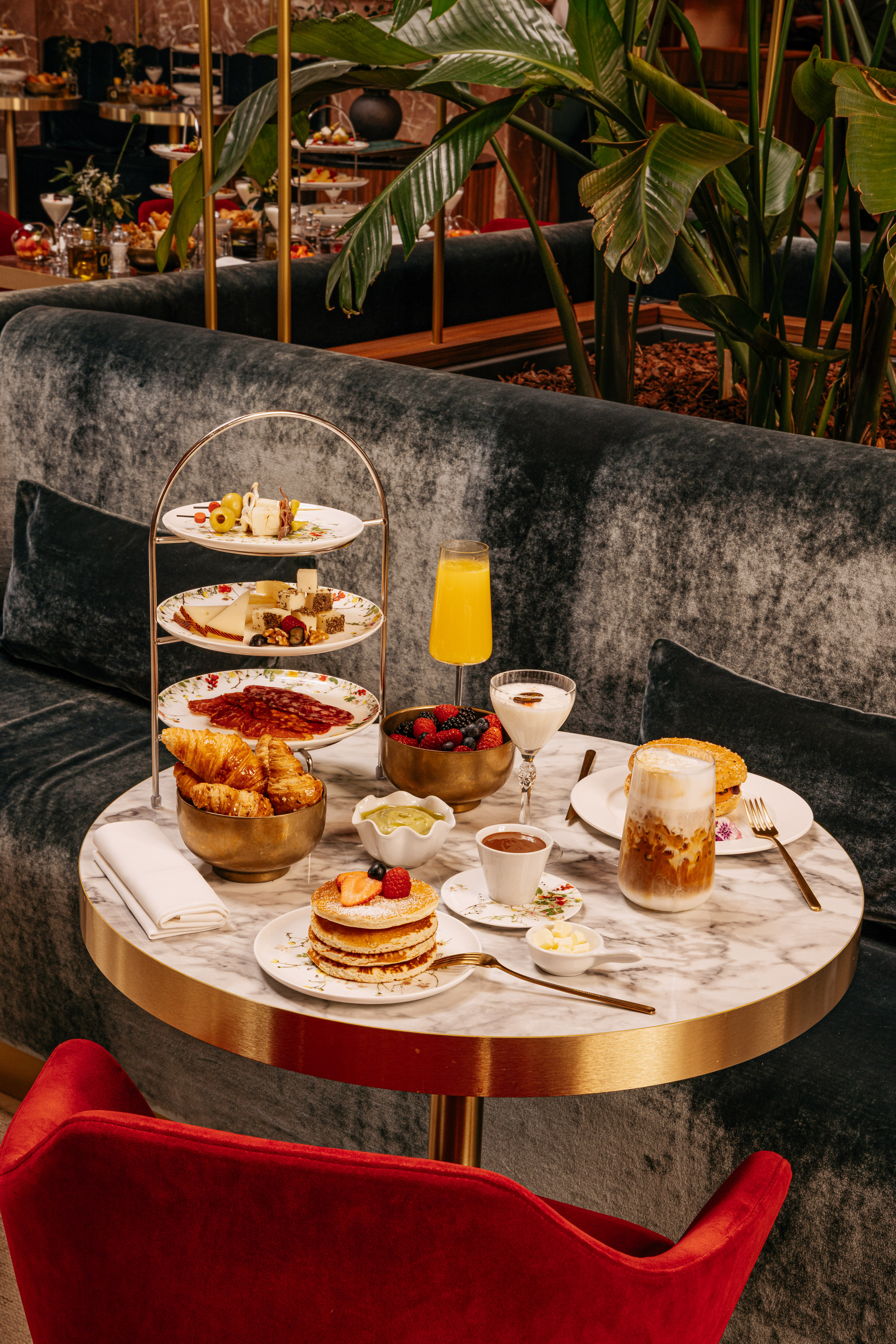 Luxury hotel brunch: pancakes, cheese, pastries, coffee on marble table.
