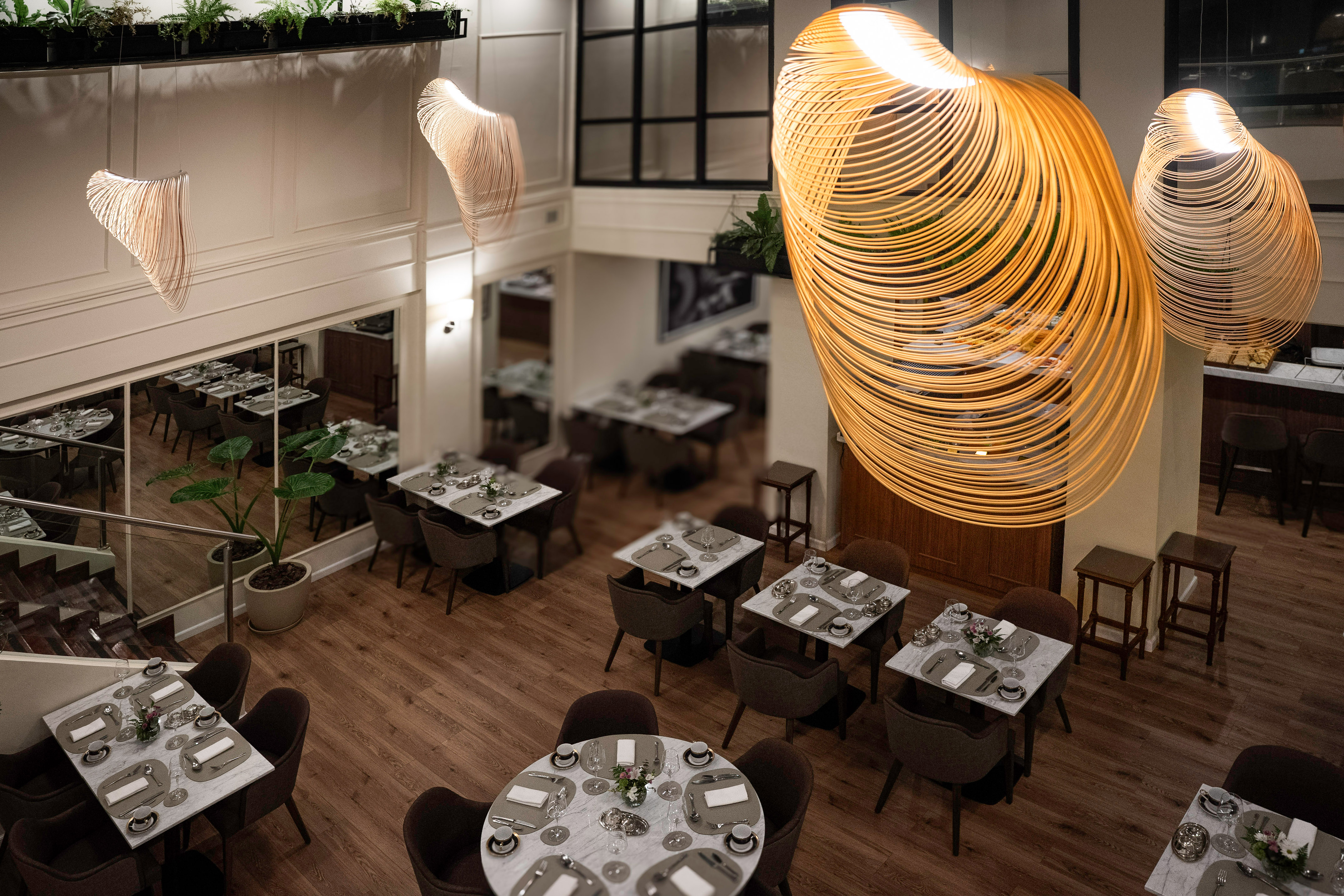 Modern restaurant dining with elegant tables and unique spiral pendant lights.