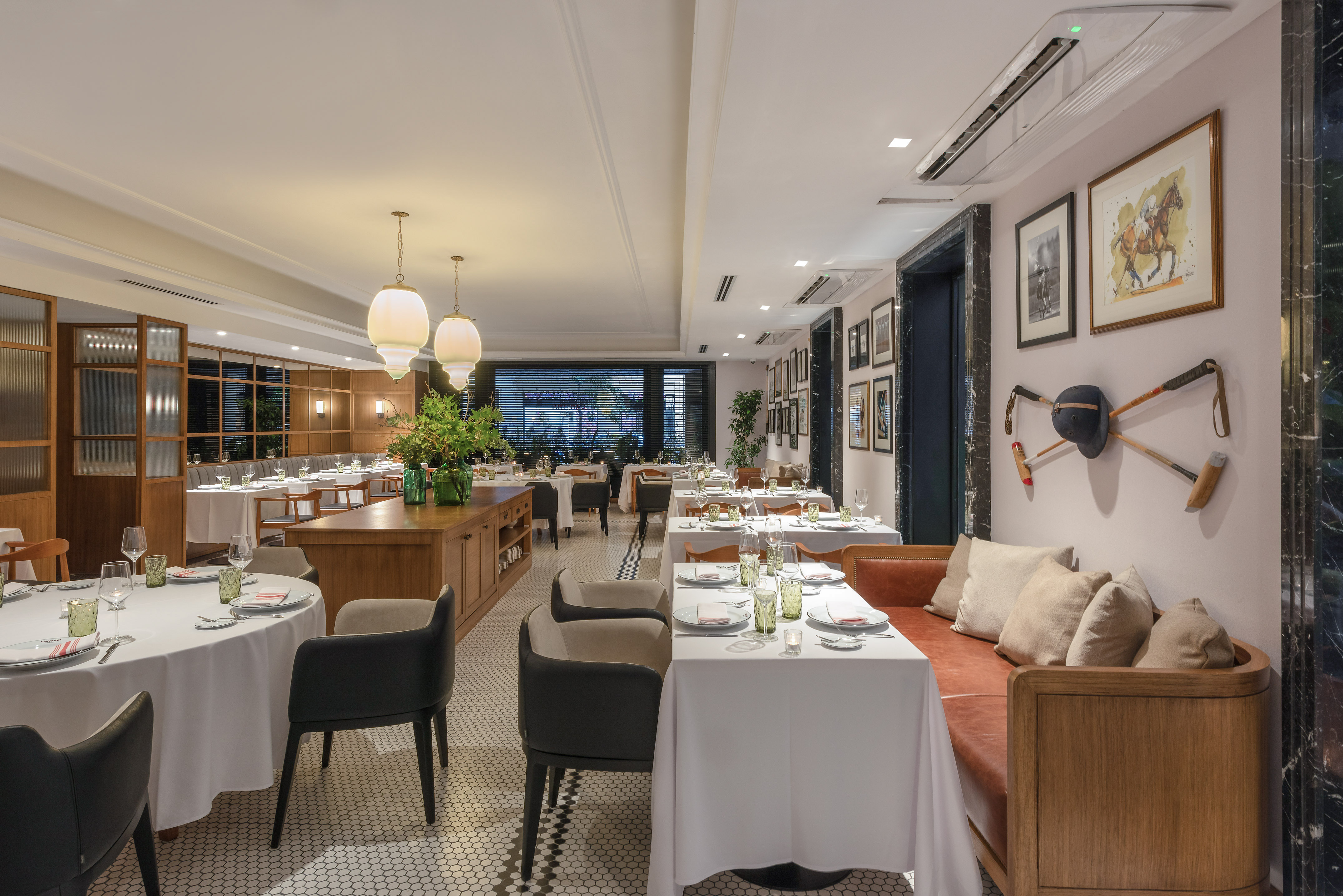 Elegant restaurant dining room with set tables, leather banquette, and unique polo decor.