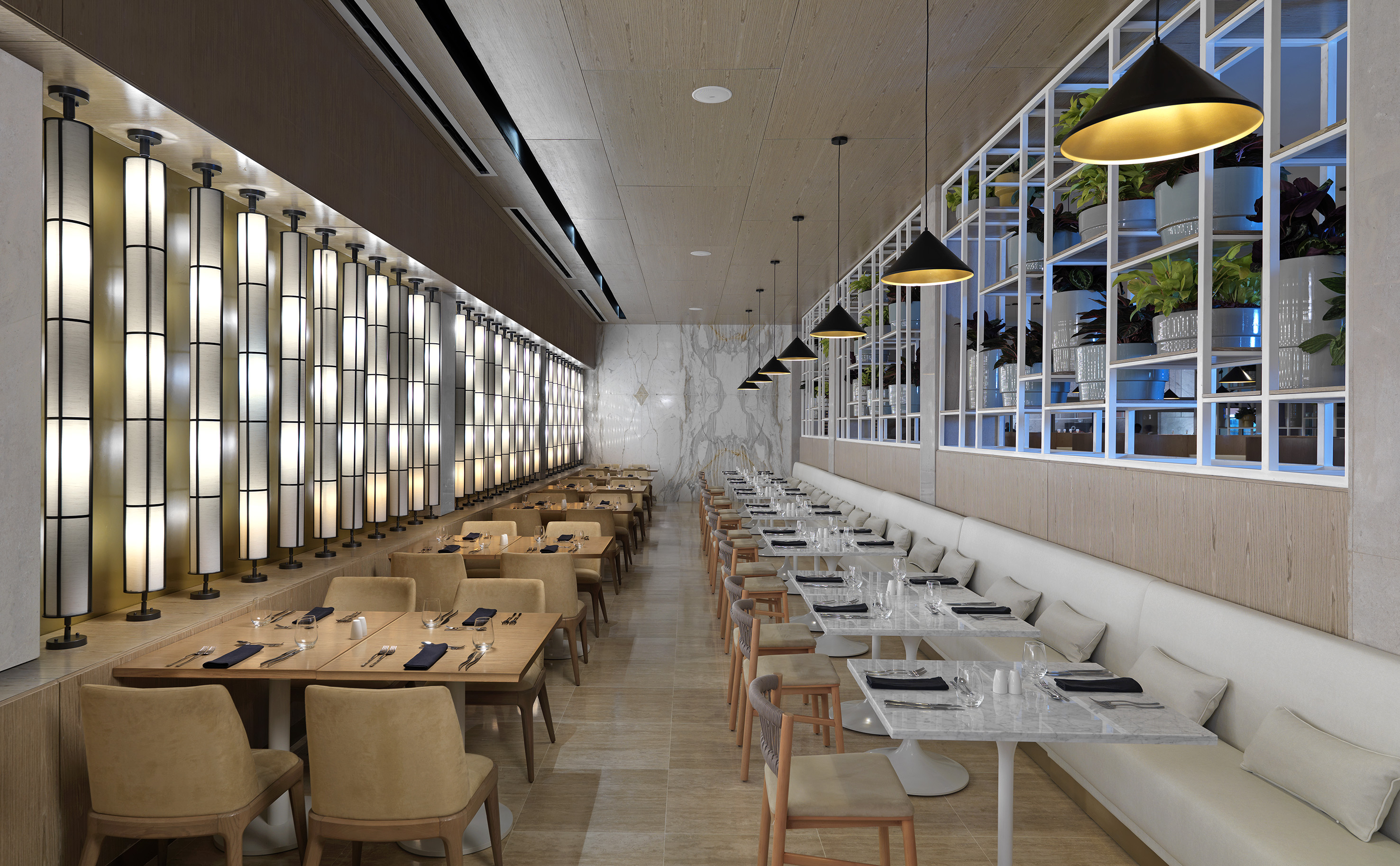Modern restaurant interior with banquette seating, wood tables, and contemporary decor.