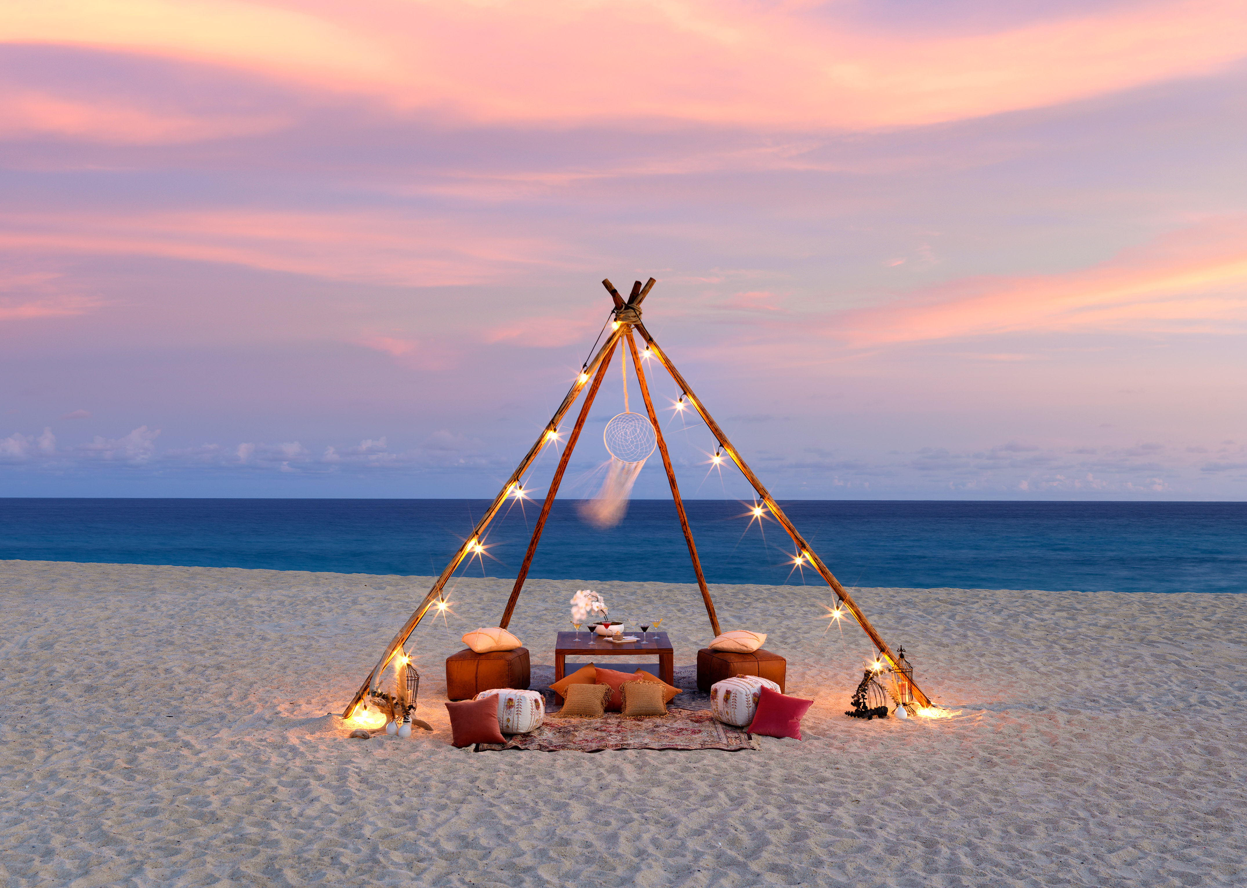 a tent on a beach with lights and a dream catcher
