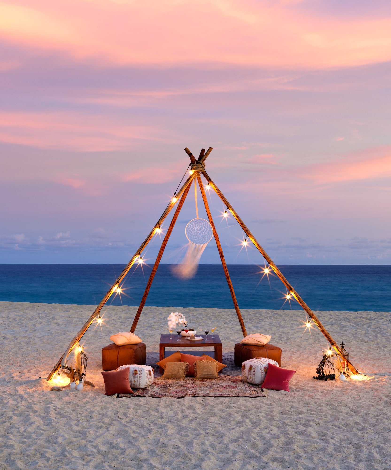 a tent on a beach with lights and a dream catcher
