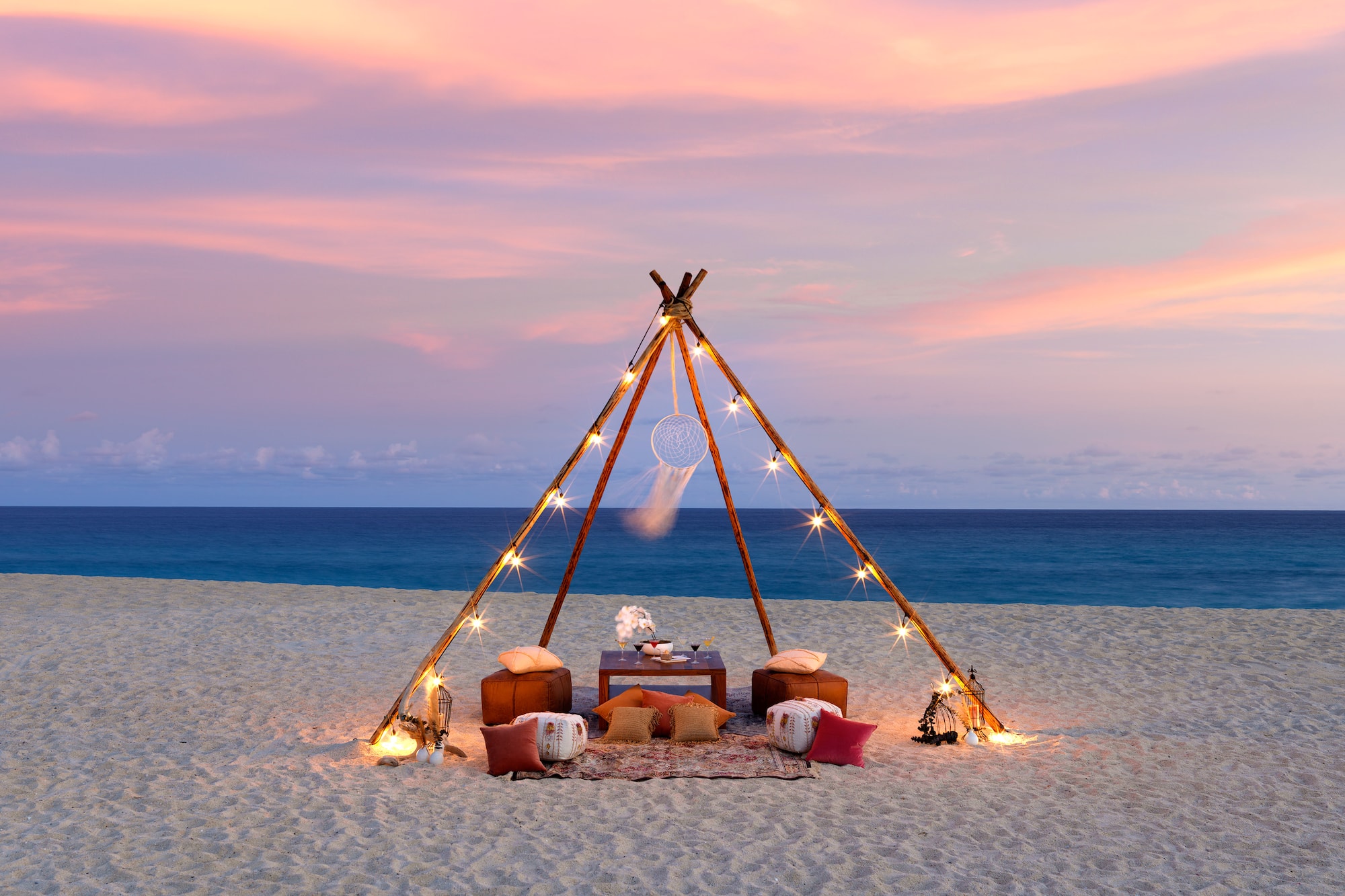 a tent on a beach with lights and a dream catcher