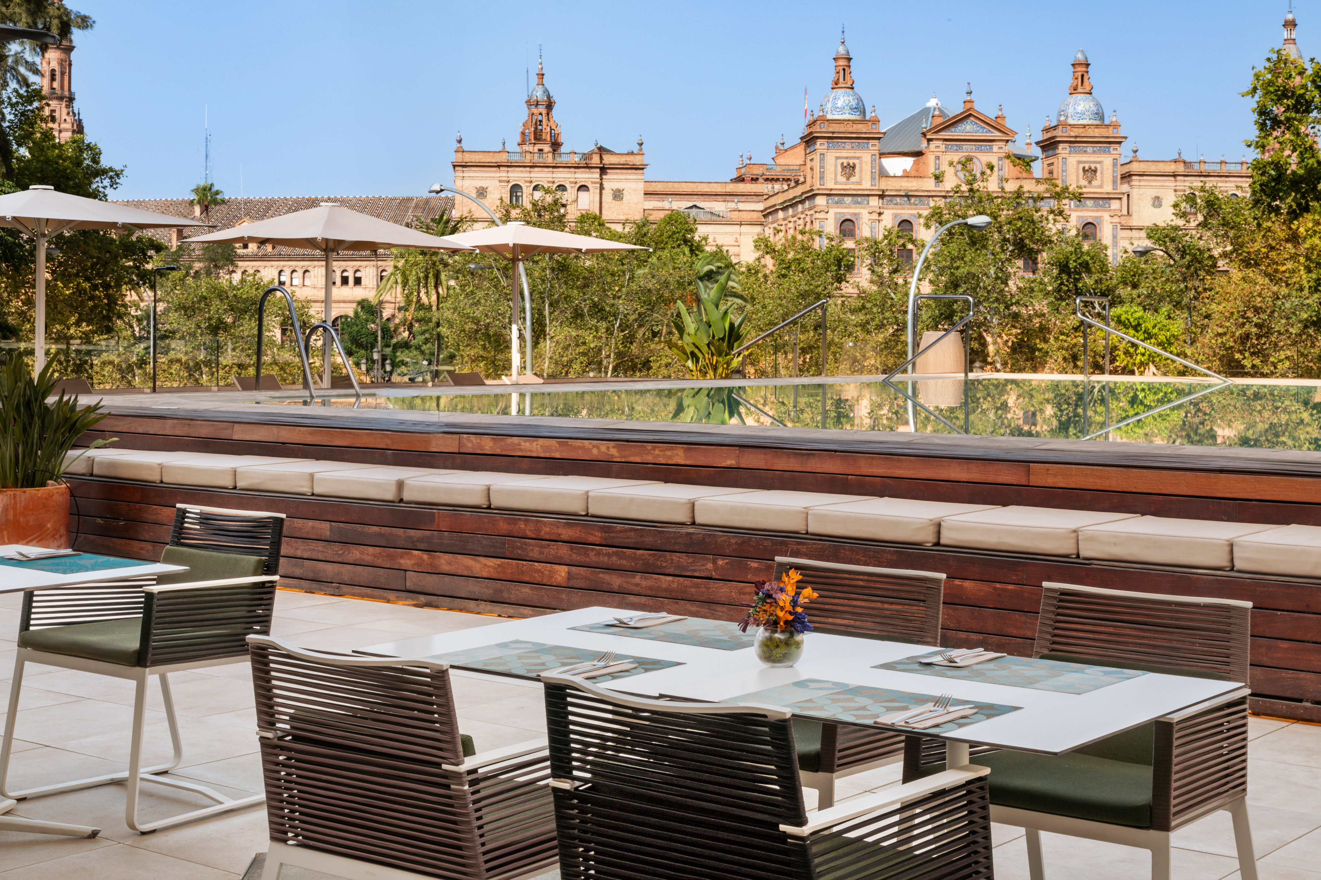 Outdoor dining terrace with pool, deck, and ornate historic building.