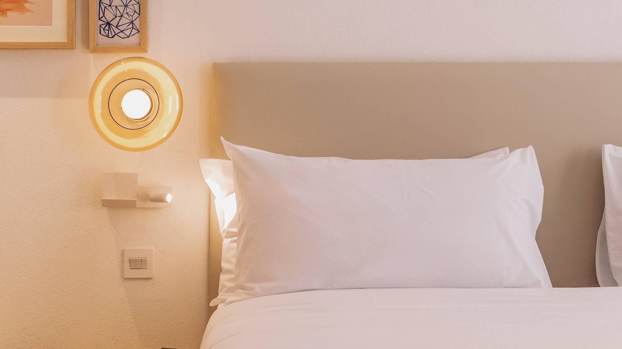 a bed with white sheets and a yellow lamp