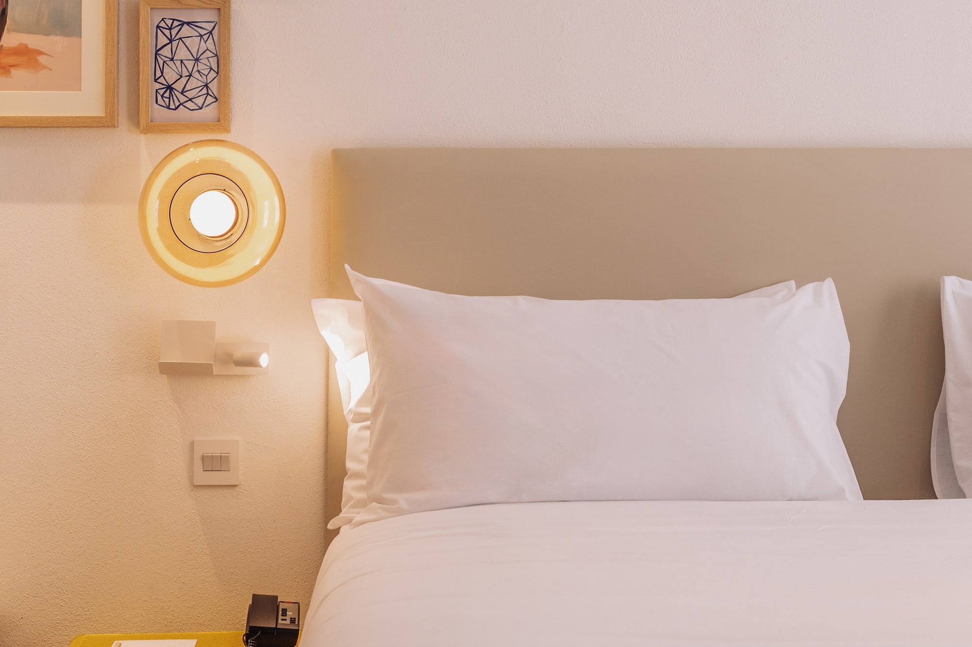 a bed with white sheets and a yellow lamp