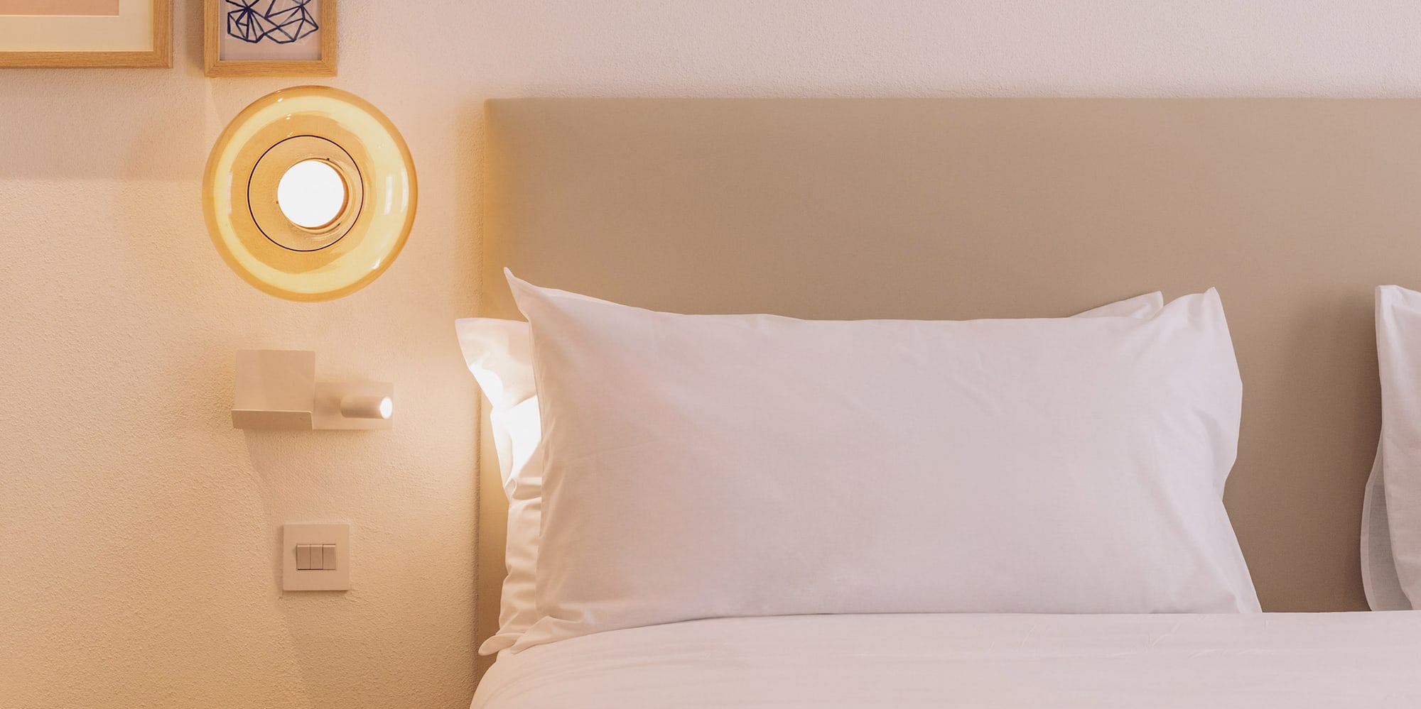 a bed with white sheets and a yellow lamp