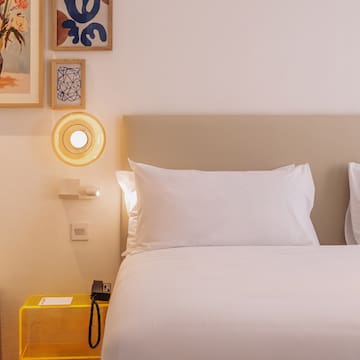 a bed with white sheets and a yellow lamp