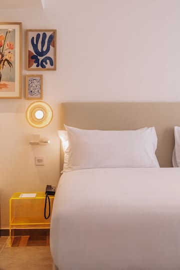 a bed with white sheets and a yellow lamp