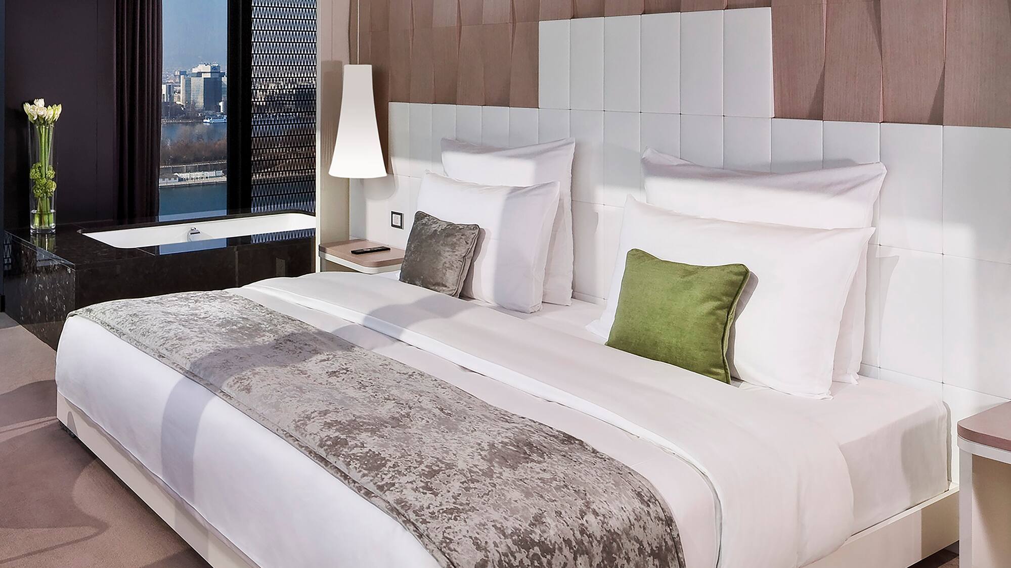 a bed with white sheets and green pillows