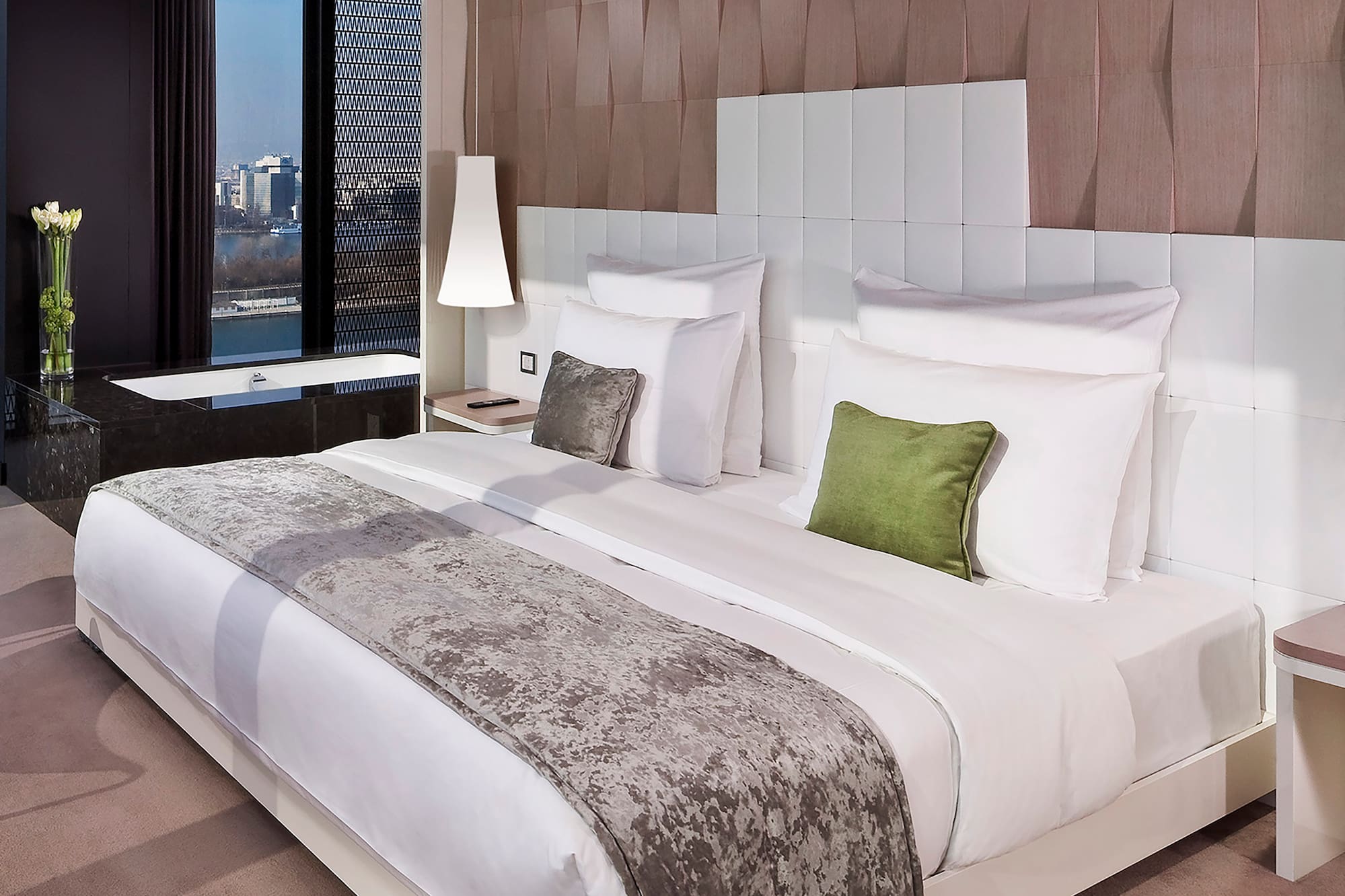 a bed with white sheets and green pillows