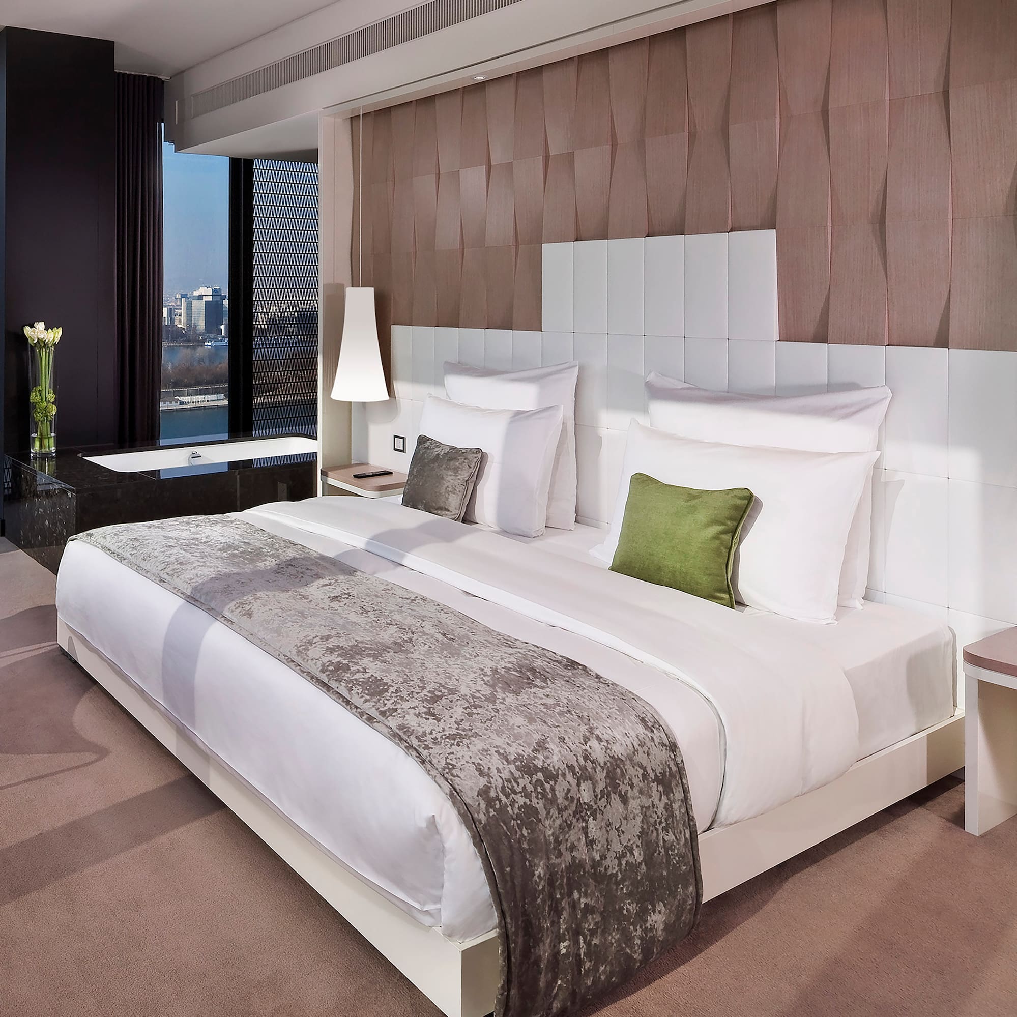 a bed with white sheets and green pillows