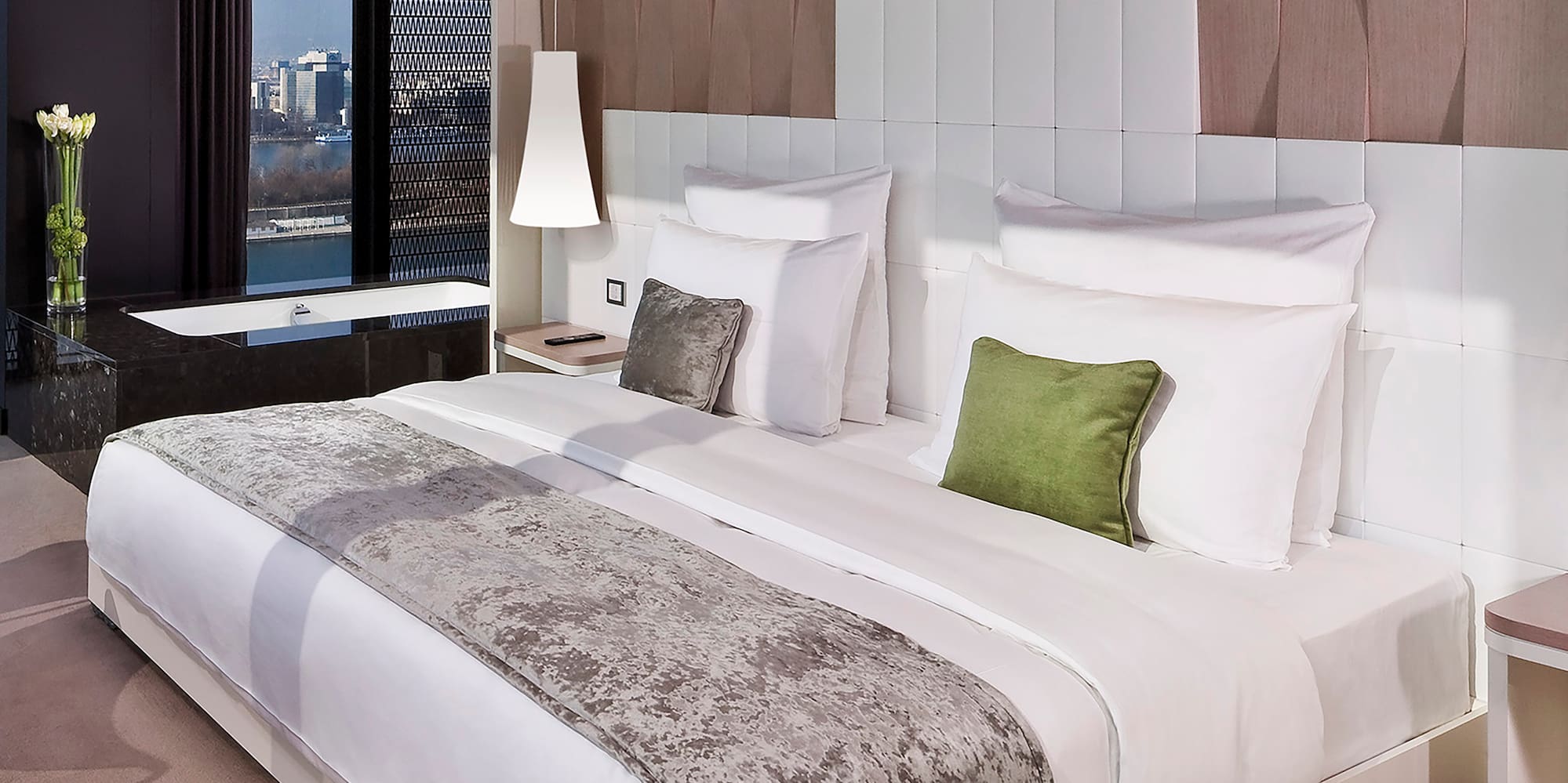 a bed with white sheets and green pillows