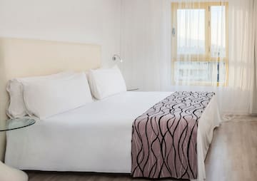 a bed with white sheets and a pink blanket