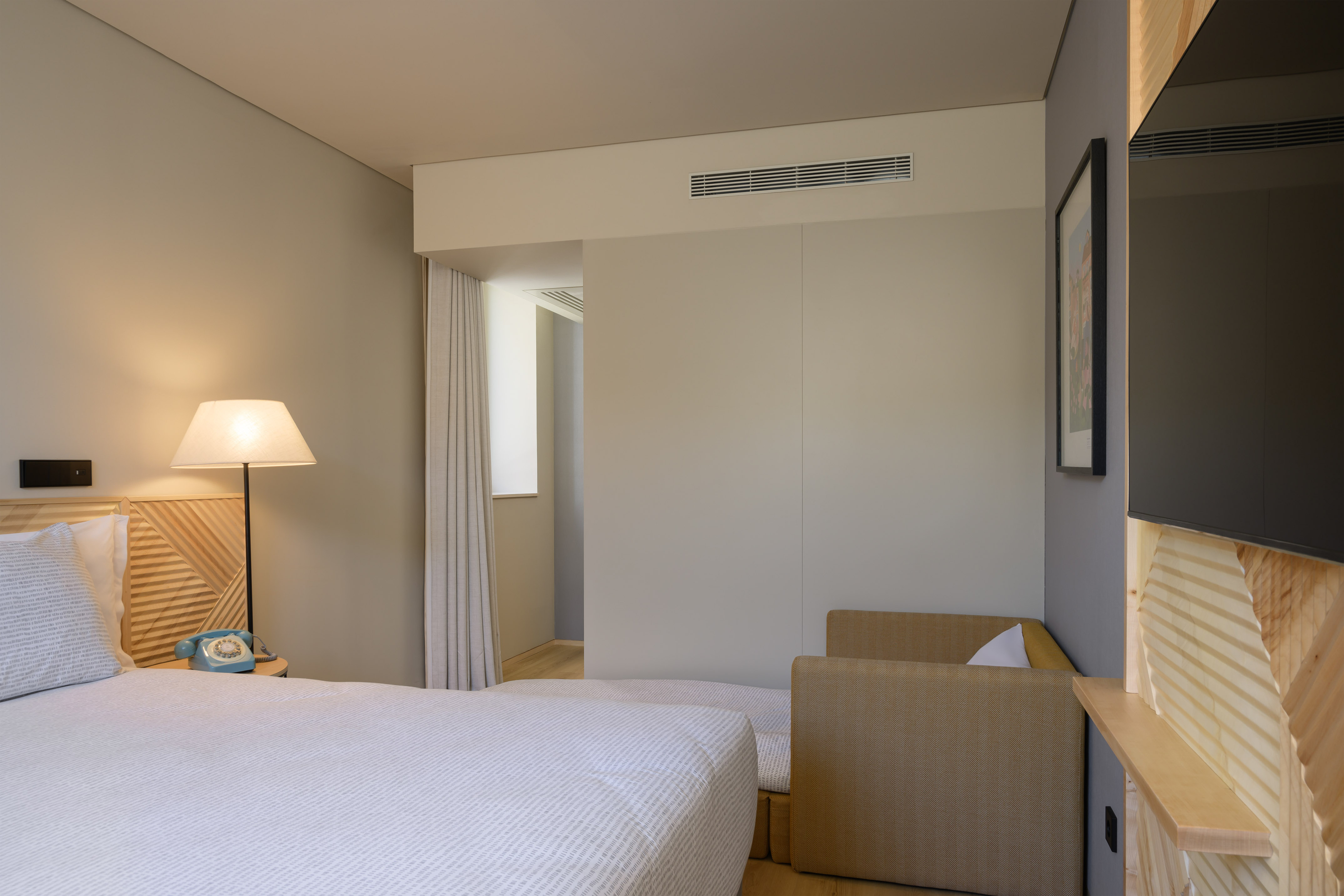 Modern hotel room with bed, vintage phone, geometric wood, and daybed.