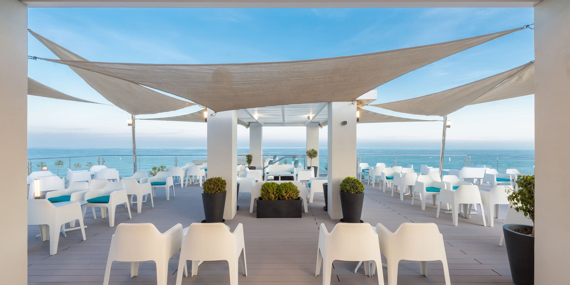 a patio with white chairs and a large white canopy over it