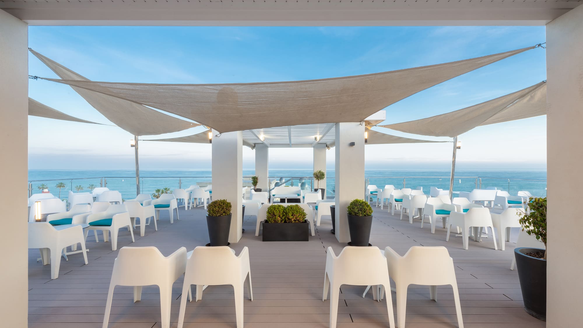 a patio with white chairs and a large white canopy over it