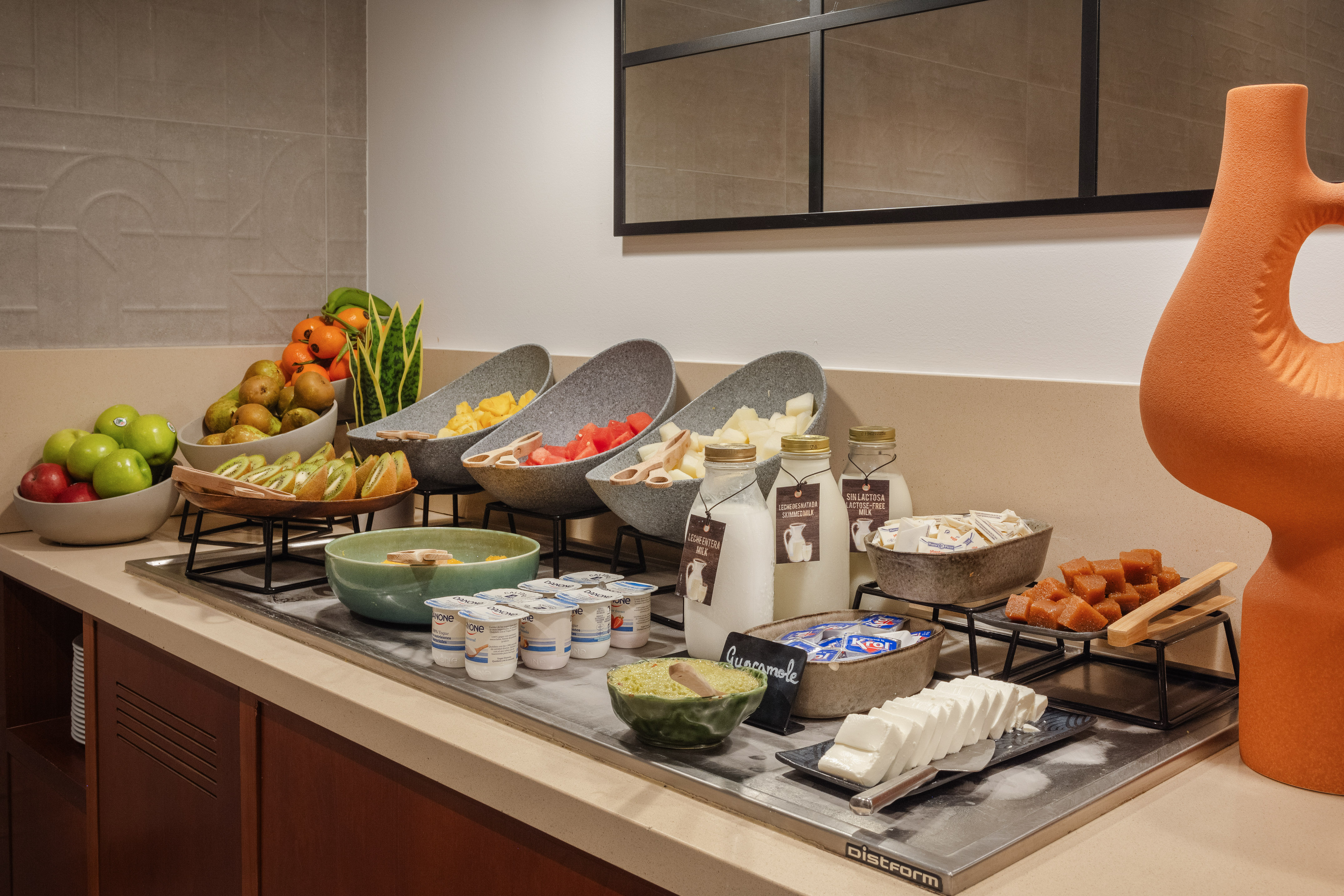 Hotel breakfast buffet with fresh fruits, yogurt, milk, guacamole, and cheese.
