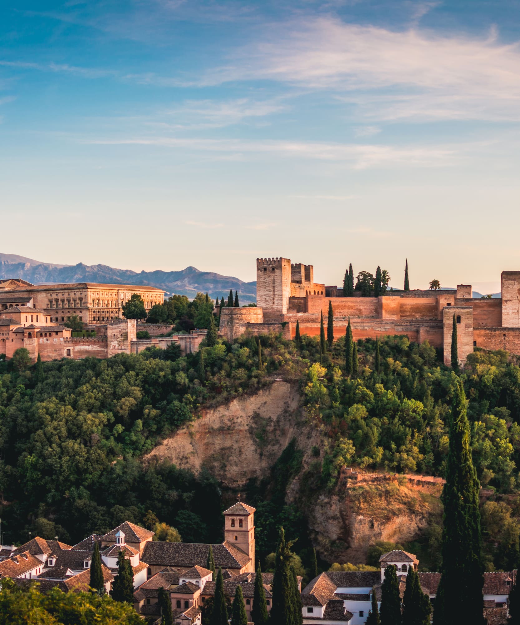 Alhambra palace and fortress, Granada, Spain, at sunset with mountains.