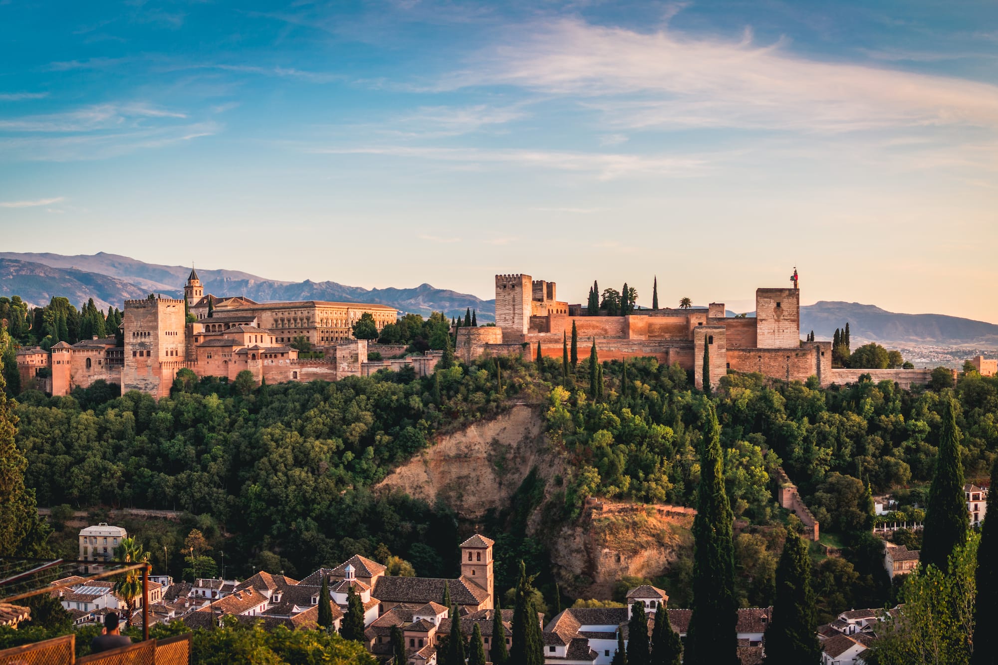 Alhambra palace and fortress, Granada, Spain, at sunset with mountains.