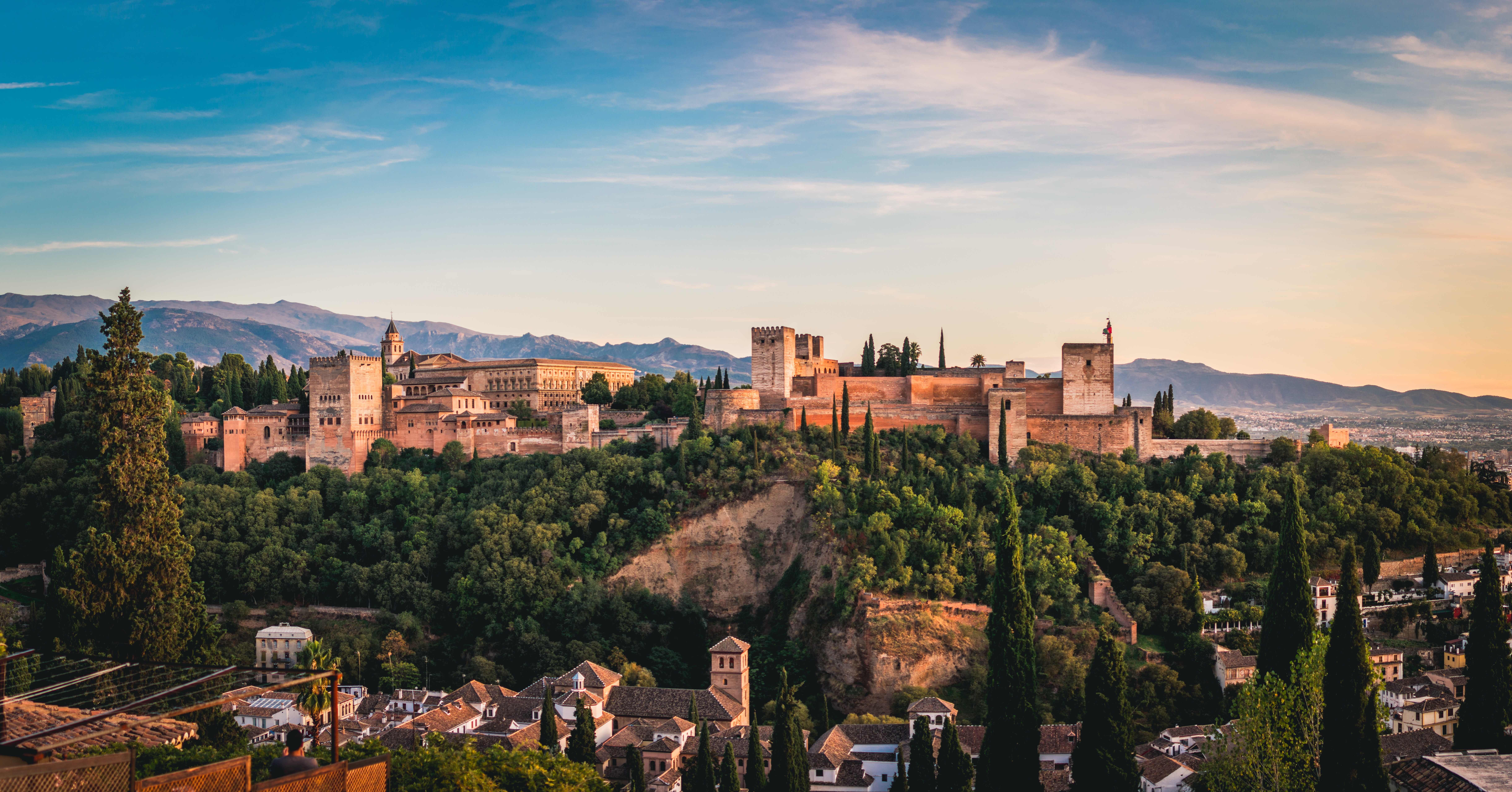 Alhambra palace and fortress, Granada, Spain, at sunset with mountains.