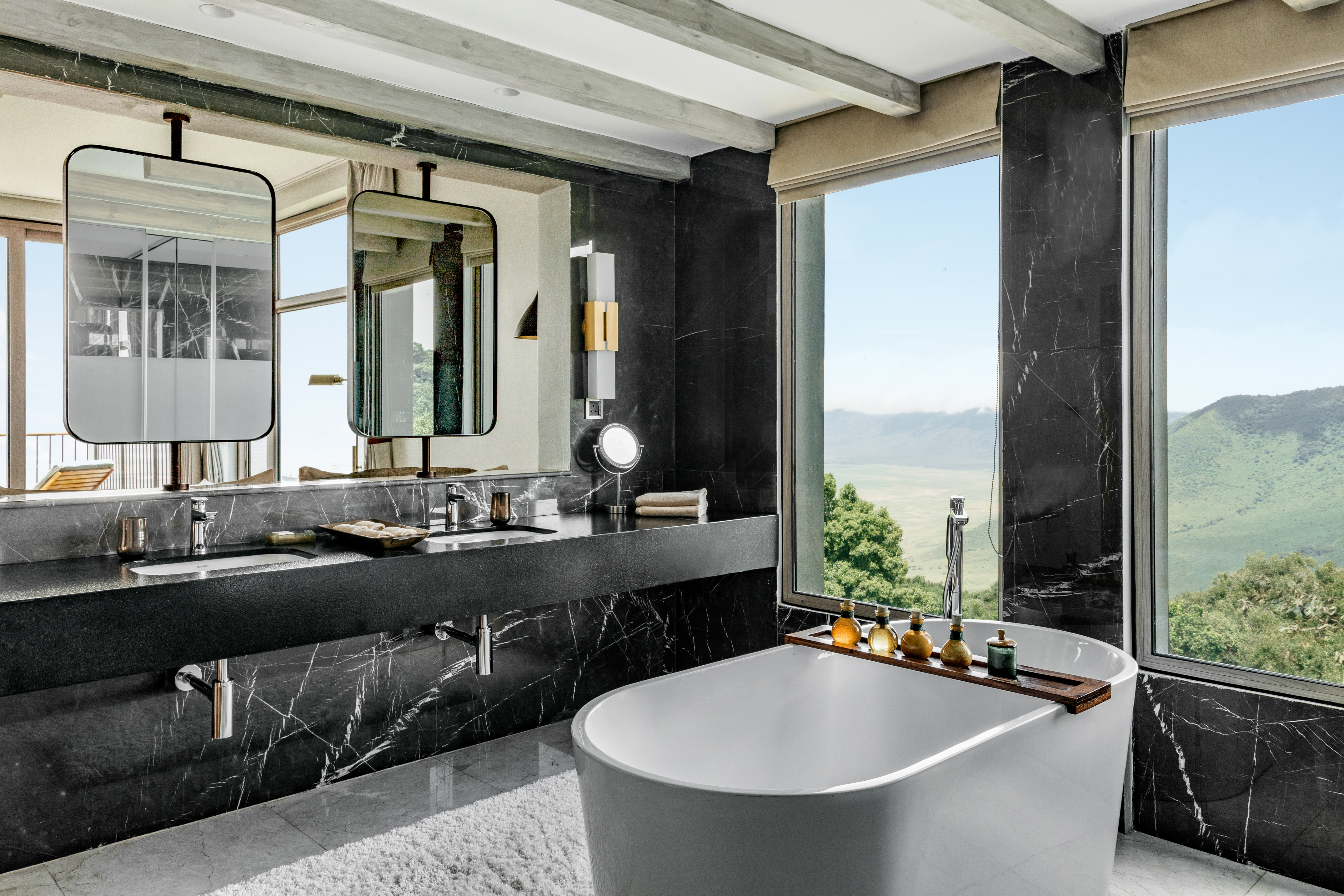 Black marble luxury bathroom, freestanding tub, panoramic valley view.