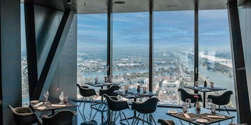 a room with tables and chairs and a view of a city and water