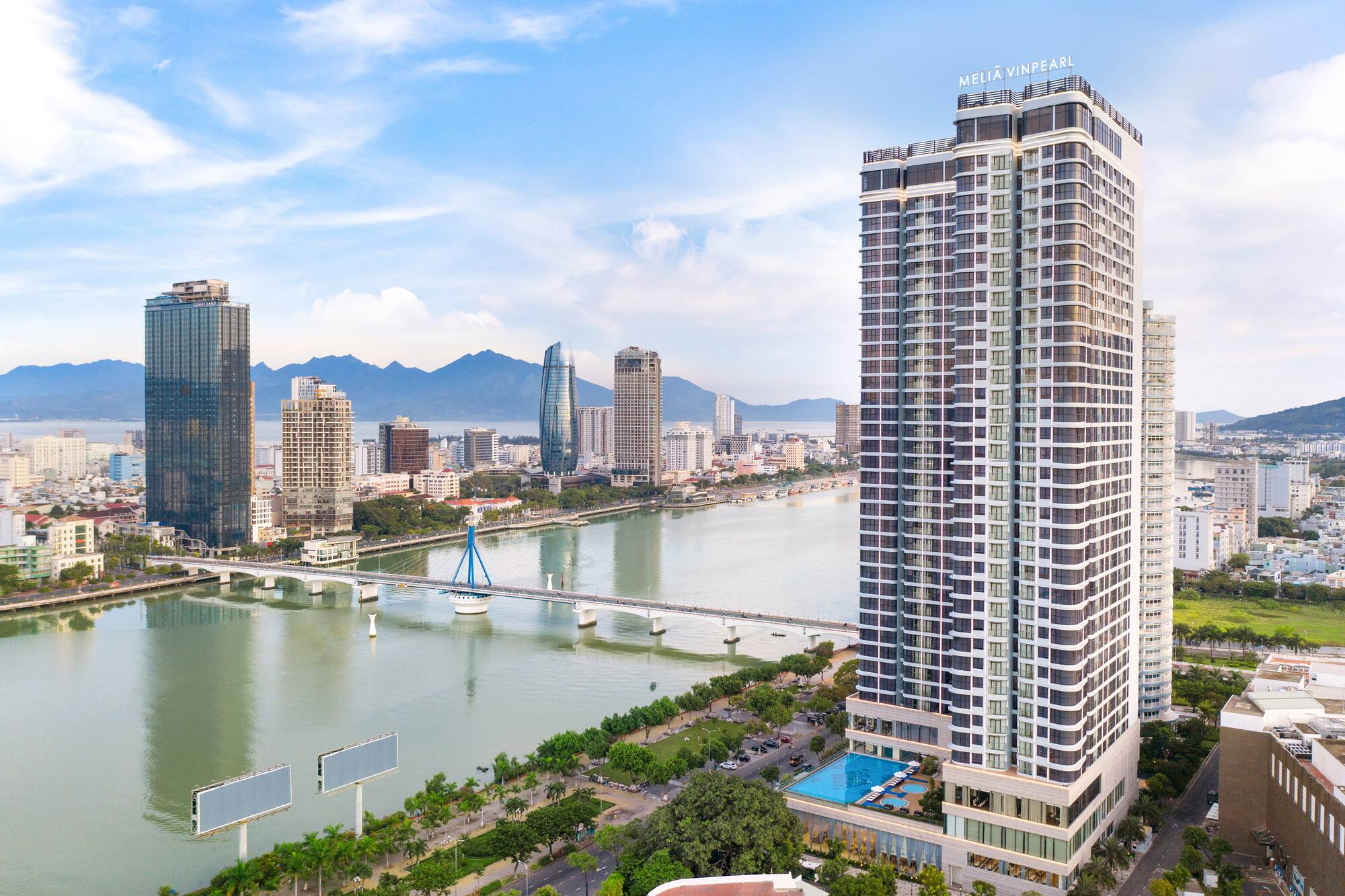 Meliá Vinpearl Da Nang hotel overlooking city, Han River, bridge, and mountains.