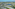 Aerial view: modern waterfront villas lining a lake, tropical trees, mountains.