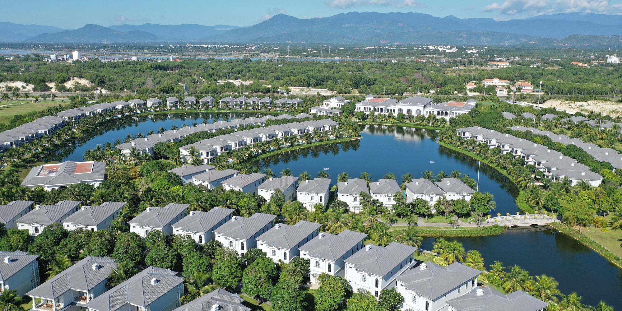 a group of houses surrounded by trees and a pond