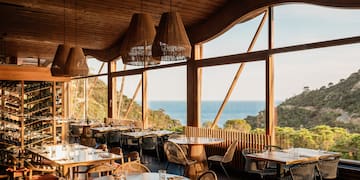 a room with tables and chairs and a view of the ocean